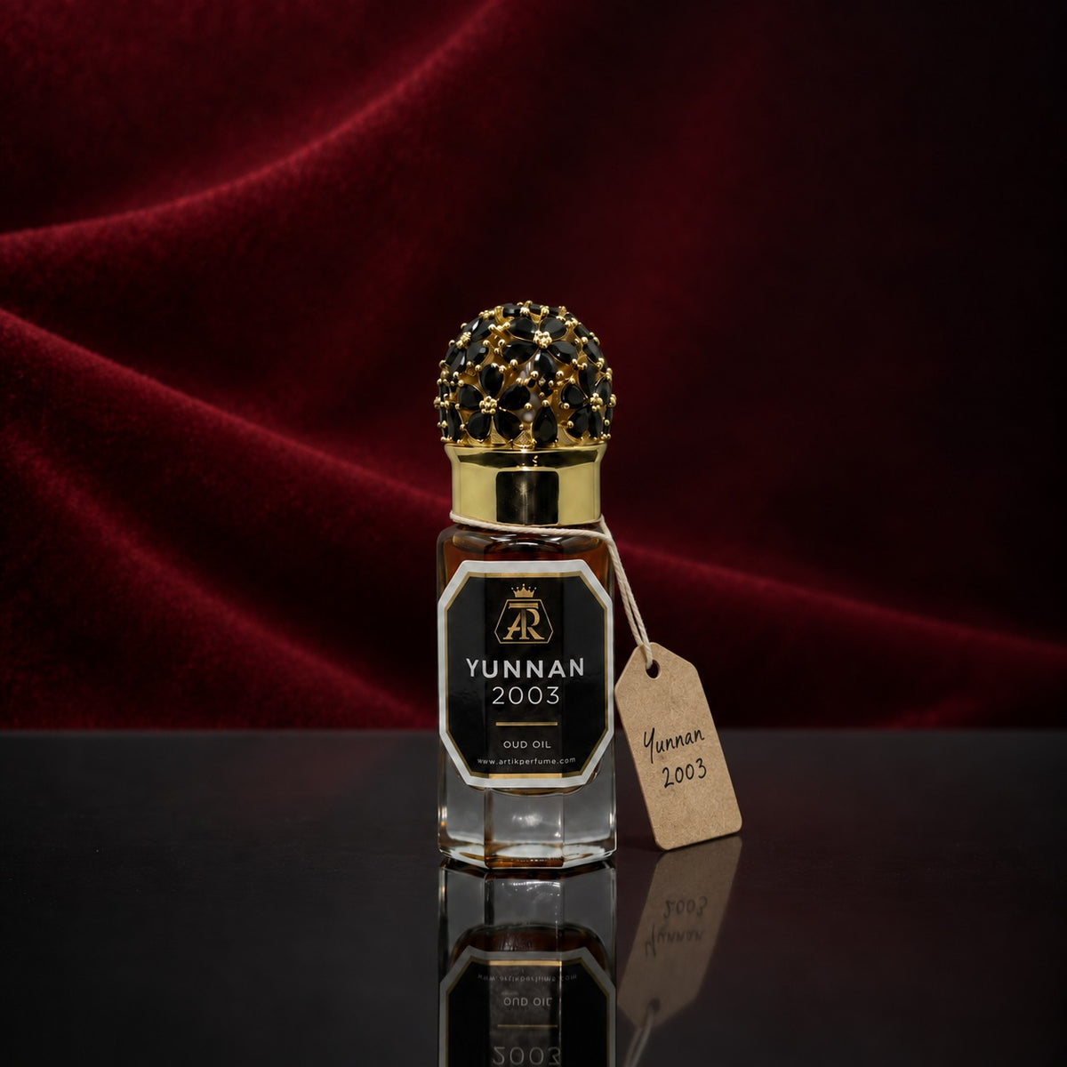 An ATTAR oud oil bottle with a jewelled cap