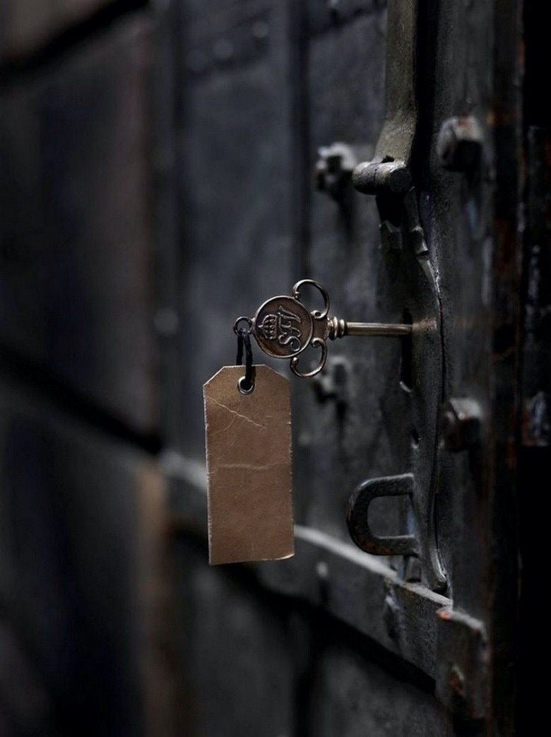 Key with a tag attached to a metal lock on a textured wall.